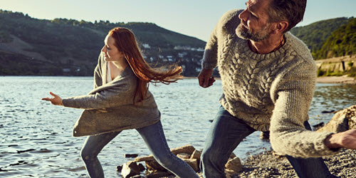 A man and woman skimming stones on a lake
